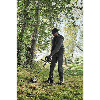 Person trimming grass with a black and yellow cordless brushless string trimmer for outdoor home improvement tasks