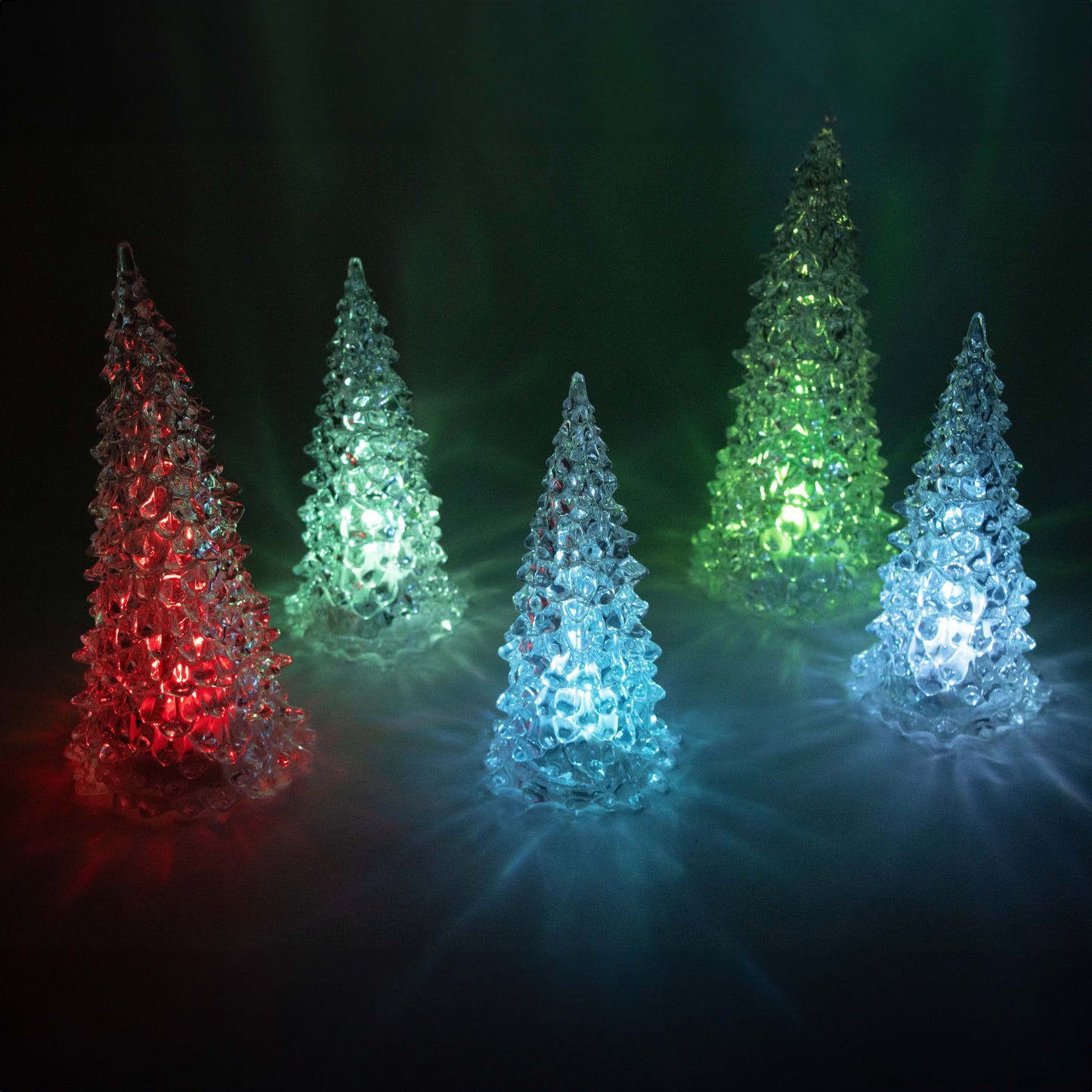 Set of five lighted translucent trees in red, blue, and green hues casting ambient seasonal glow