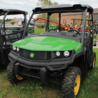 Green full-size John Deere utility vehicle with protective roof and rugged tires suitable for outdoor work and home improvement tasks