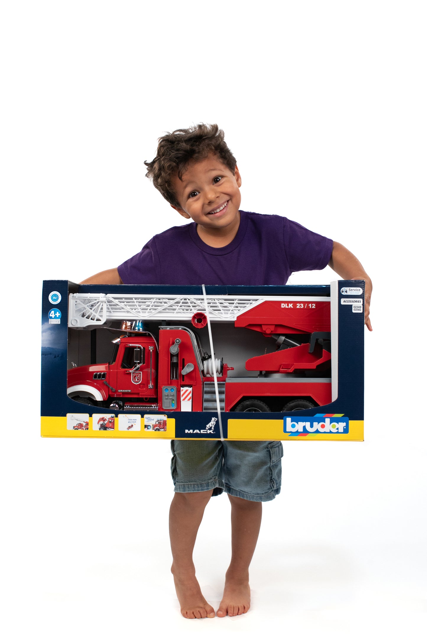 Young child holding large boxed Bruder Toys red fire engine with extendable ladder and water pump features