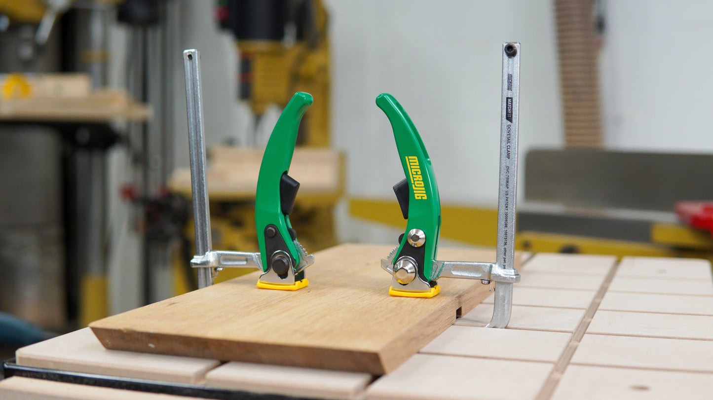 Green-handled dovetail ratchet clamps securing wood on a workbench for woodworking and home improvement tasks