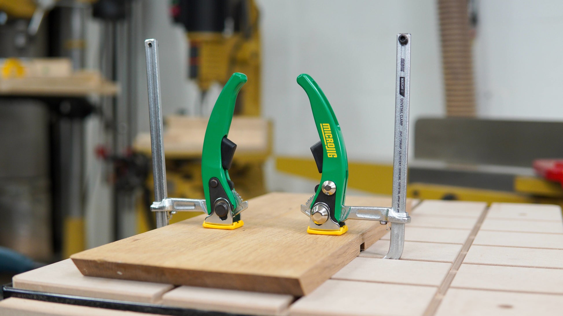 Green-handled dovetail ratchet clamps securing wood on a workbench for woodworking and home improvement tasks