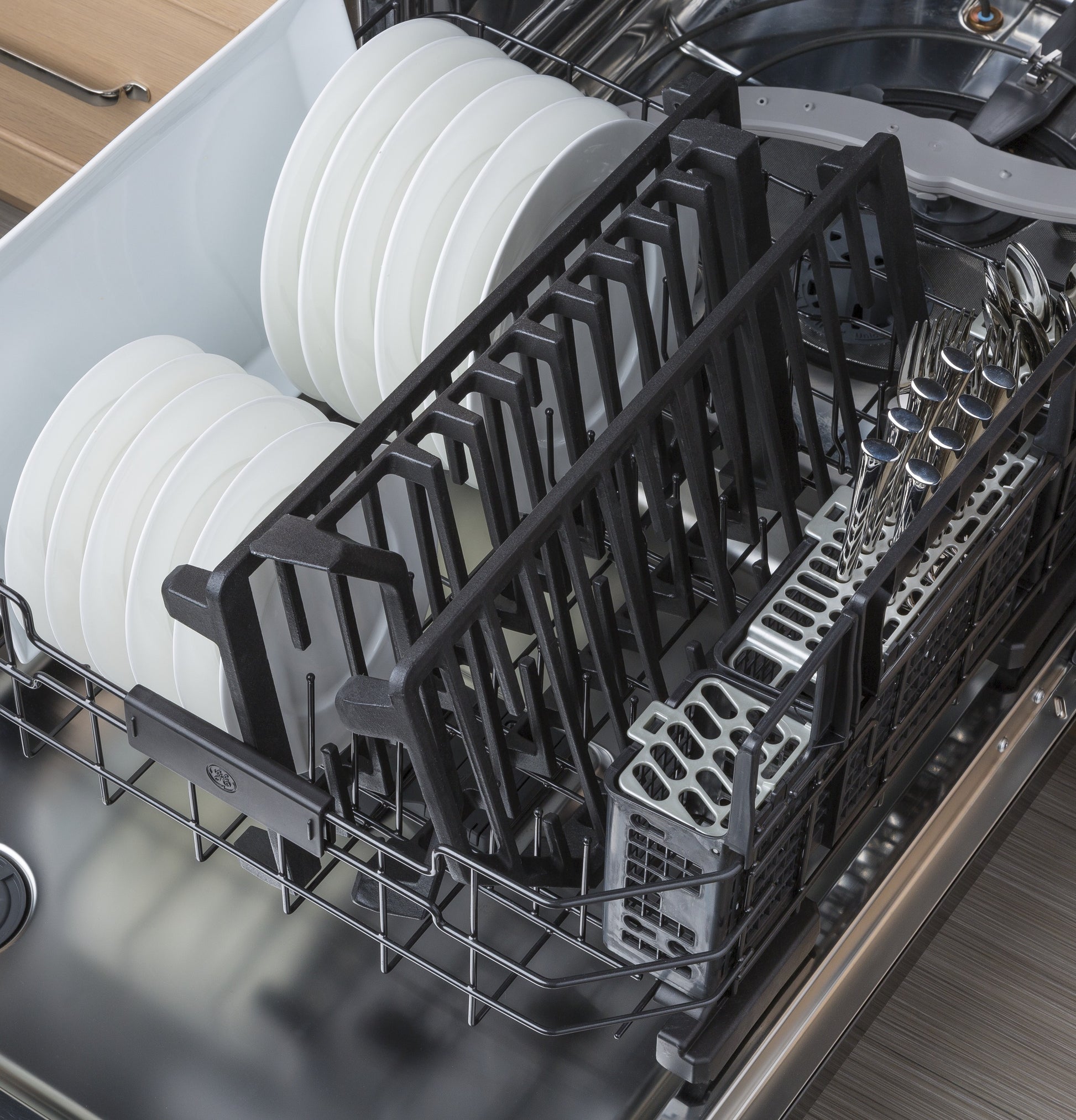 Open dishwasher loaded with clean plates, grates, and utensils in a modern kitchen appliance setup