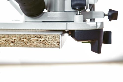 Close-up of a trim router cutting a groove in particle board for precise woodworking and home improvement projects