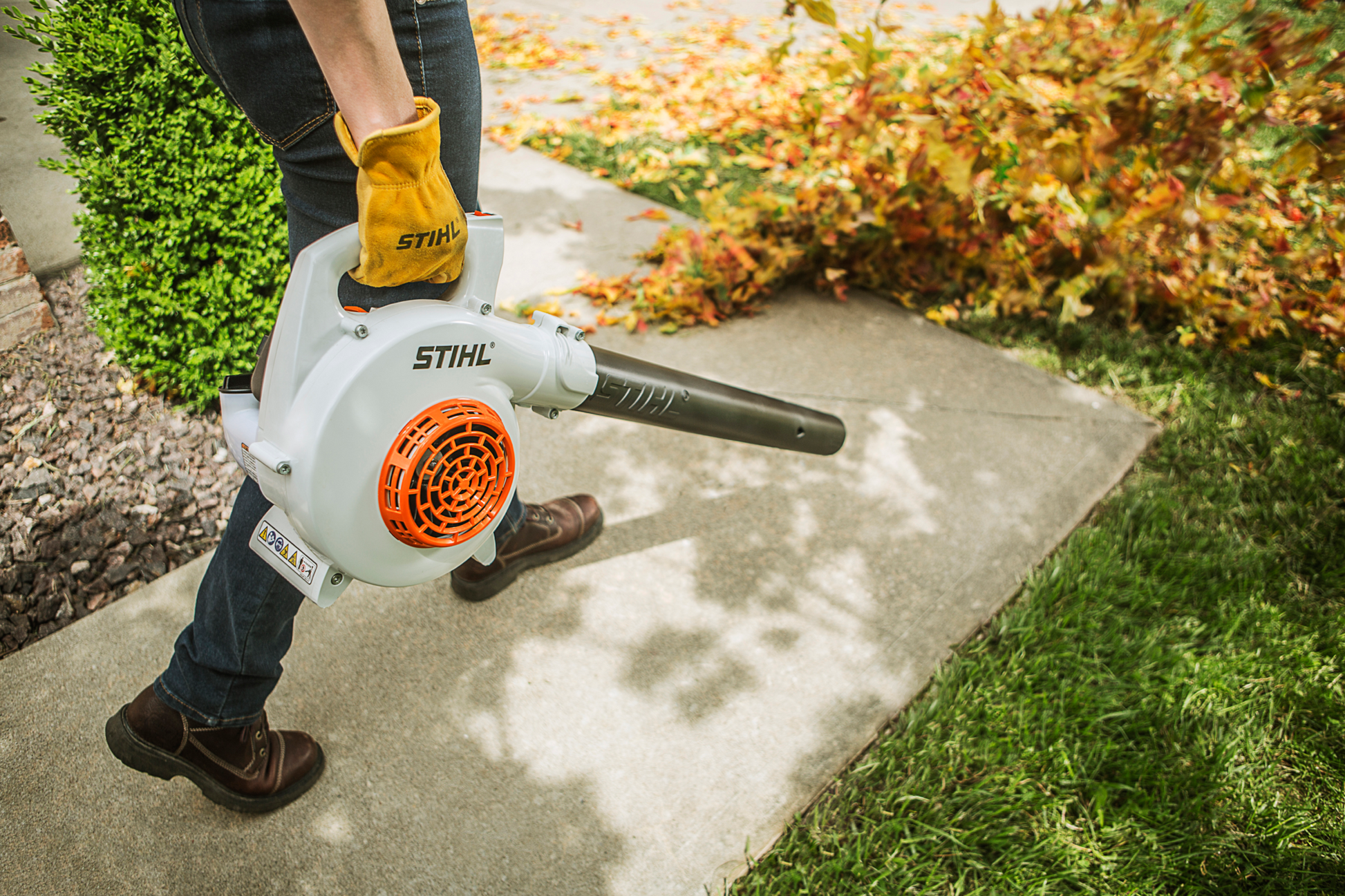 White and orange handheld gas blower with ergonomic grip used for outdoor home improvement and garden cleanup tasks