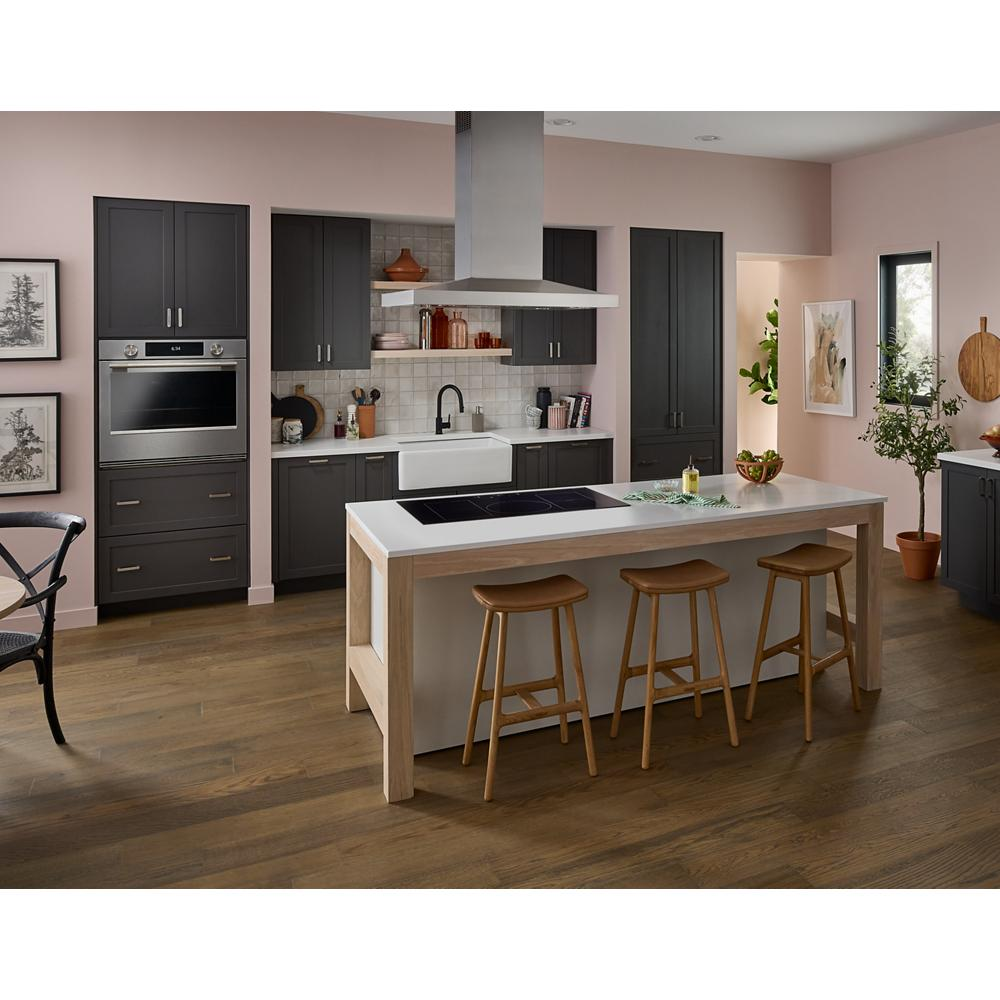 Modern kitchen with black cabinetry, wooden stools, and a 36" induction cooktop integrated into a kitchen island