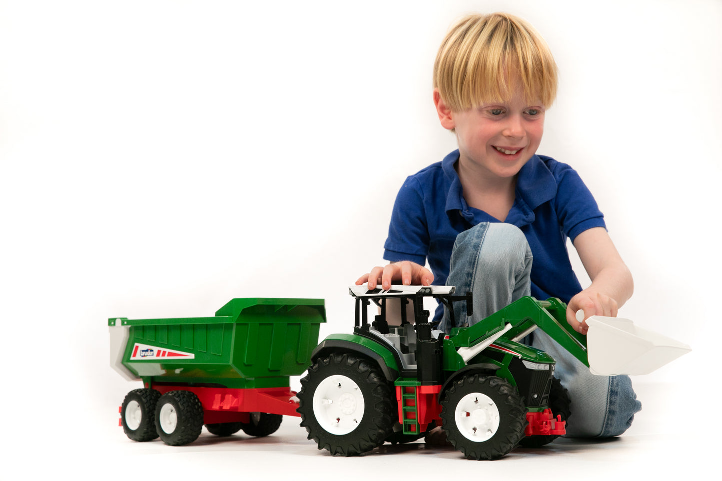 Child playing with Bruder green toy tractor featuring front loader and tipping trailer from Toys & Games collection