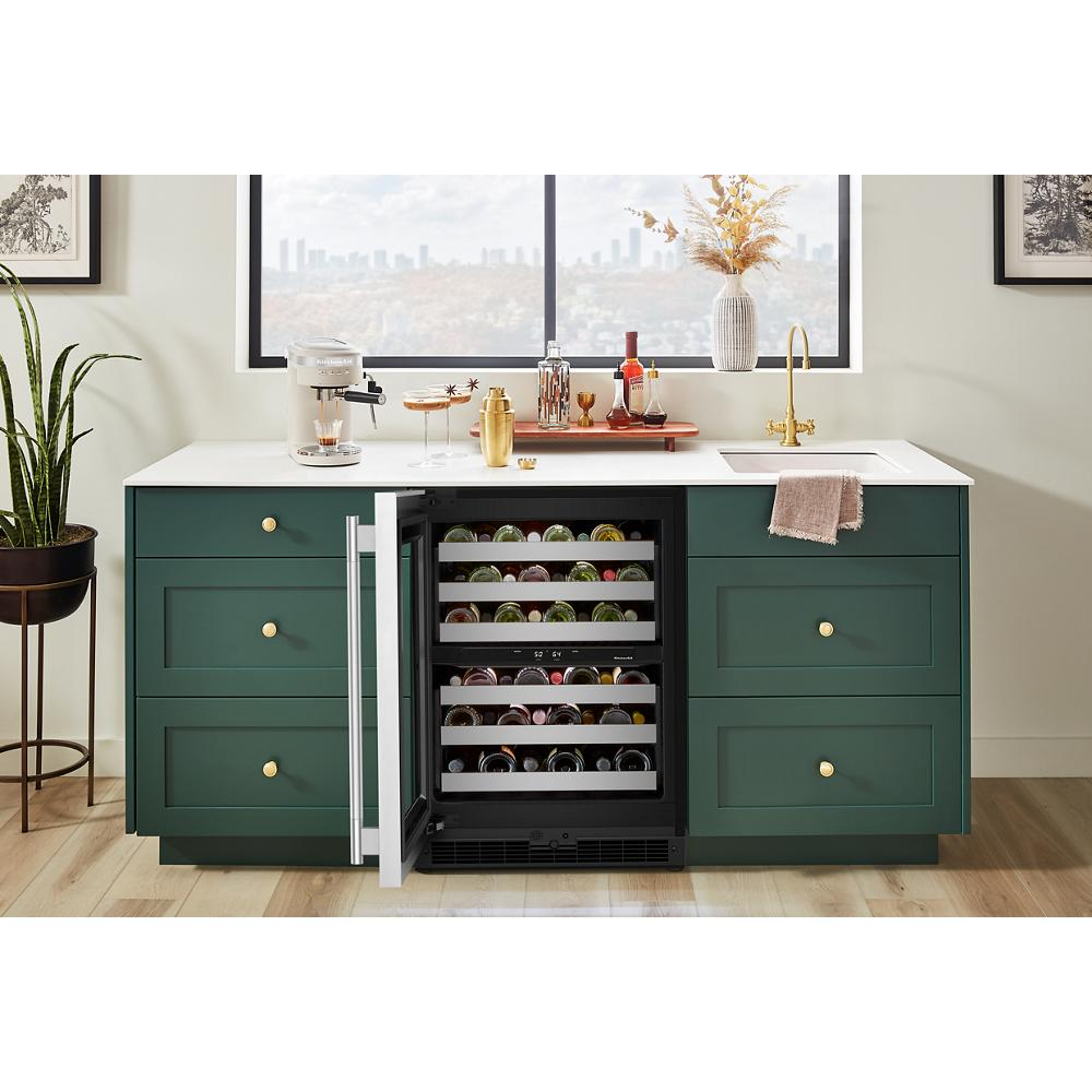 Undercounter wine refrigerator with full-extension metal racks integrated into green kitchen cabinetry and topped with white countertop
