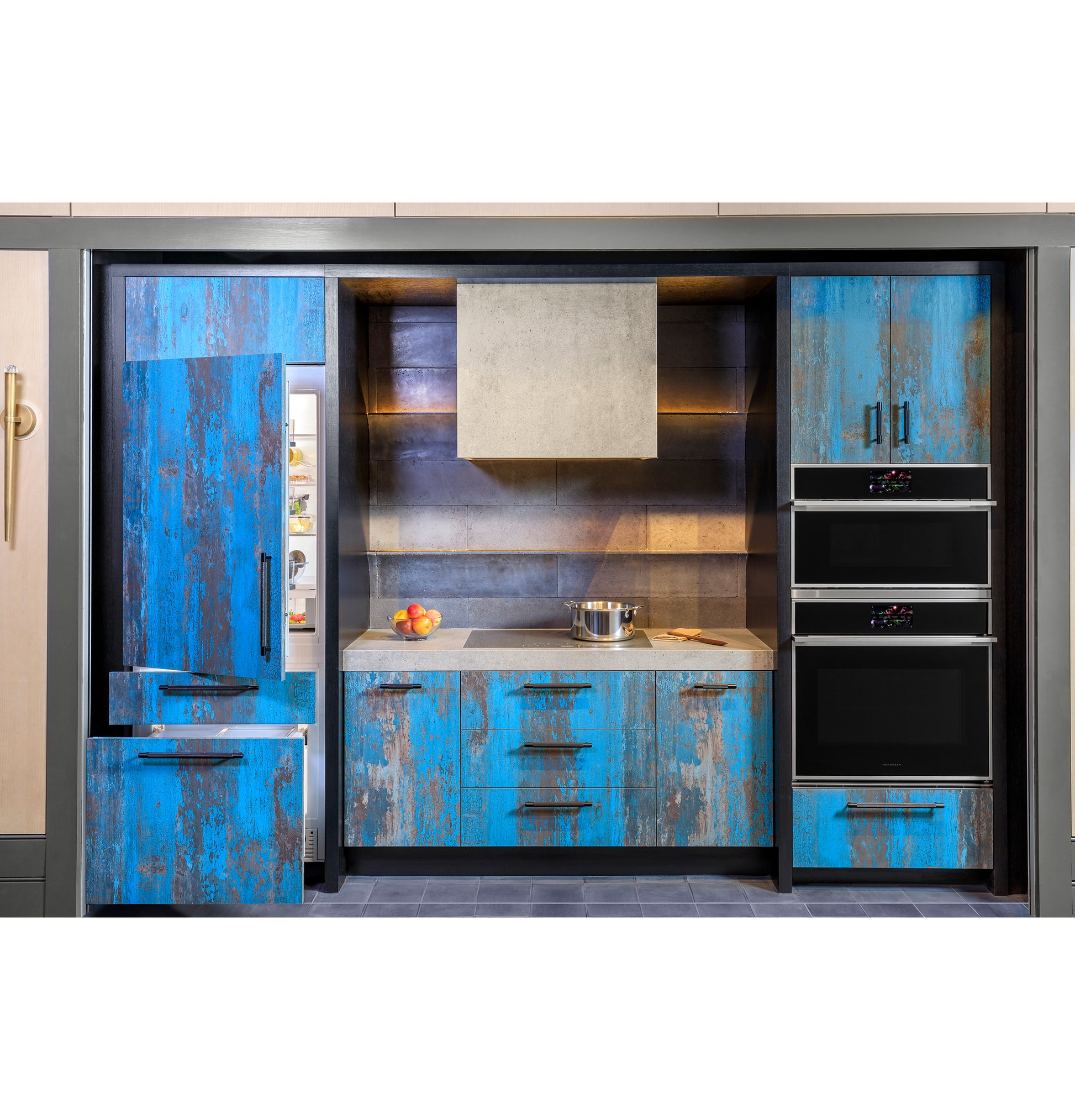 Modern kitchen with distressed blue cabinets, dual built-in wall ovens, and open refrigerator in appliances collection