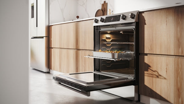 Modern stainless steel electric freestanding range with open oven and baking tray inside kitchen setting