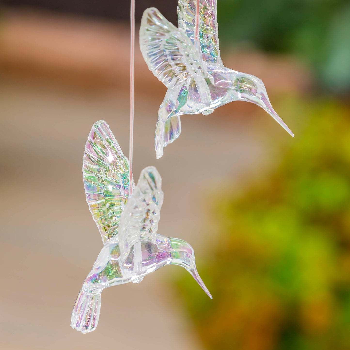 Pair of iridescent hummingbird mobiles with solar-powered color-changing effect for decorative outdoor accents
