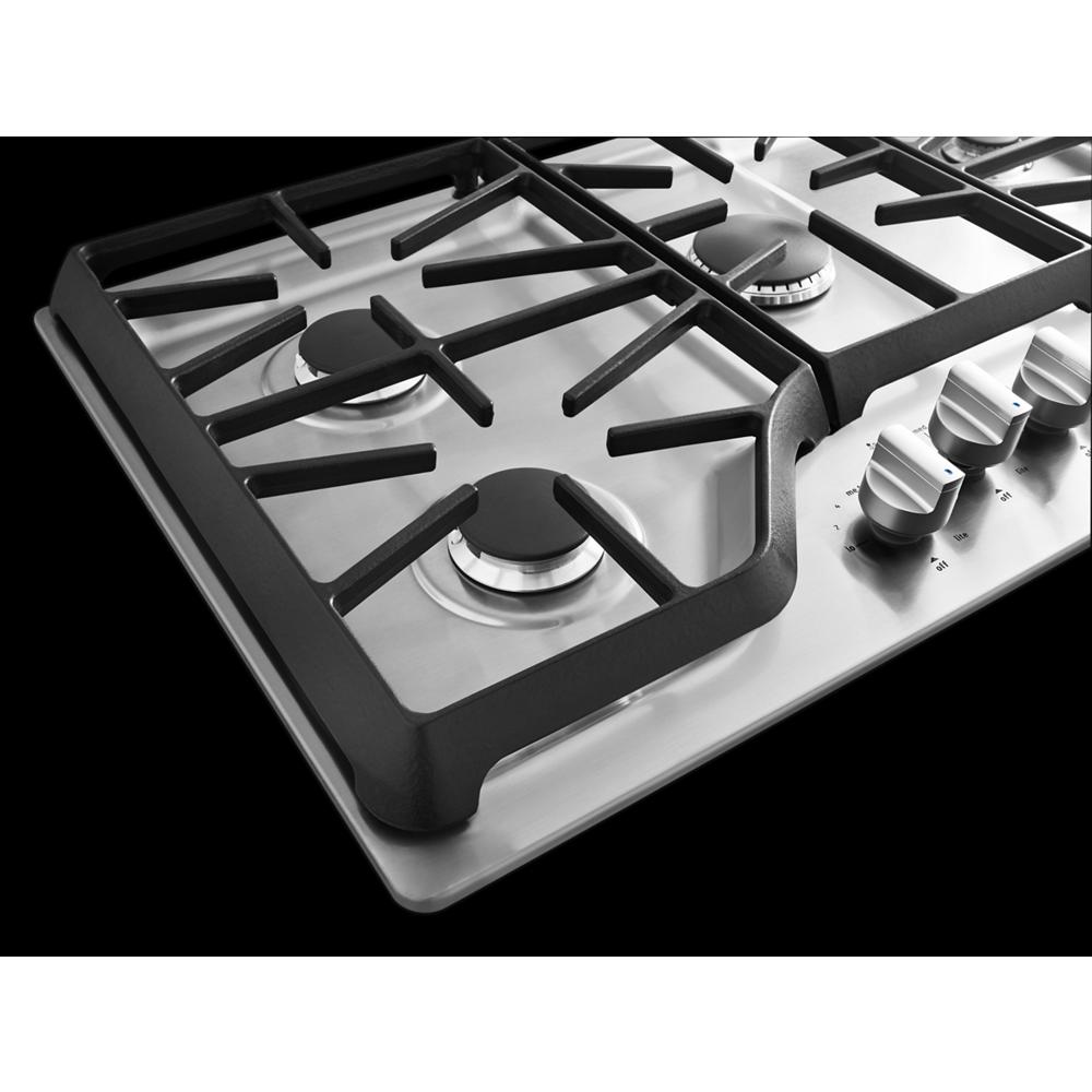Stainless steel gas cooktop with black cast iron grates and control knobs in home improvement appliances collection