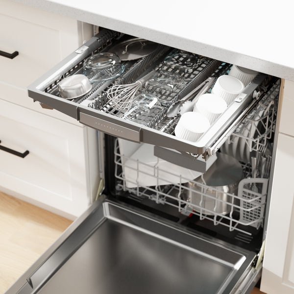 Open stainless steel dishwasher showing upper rack with cups, utensils, and kitchen tools in a modern kitchen setting