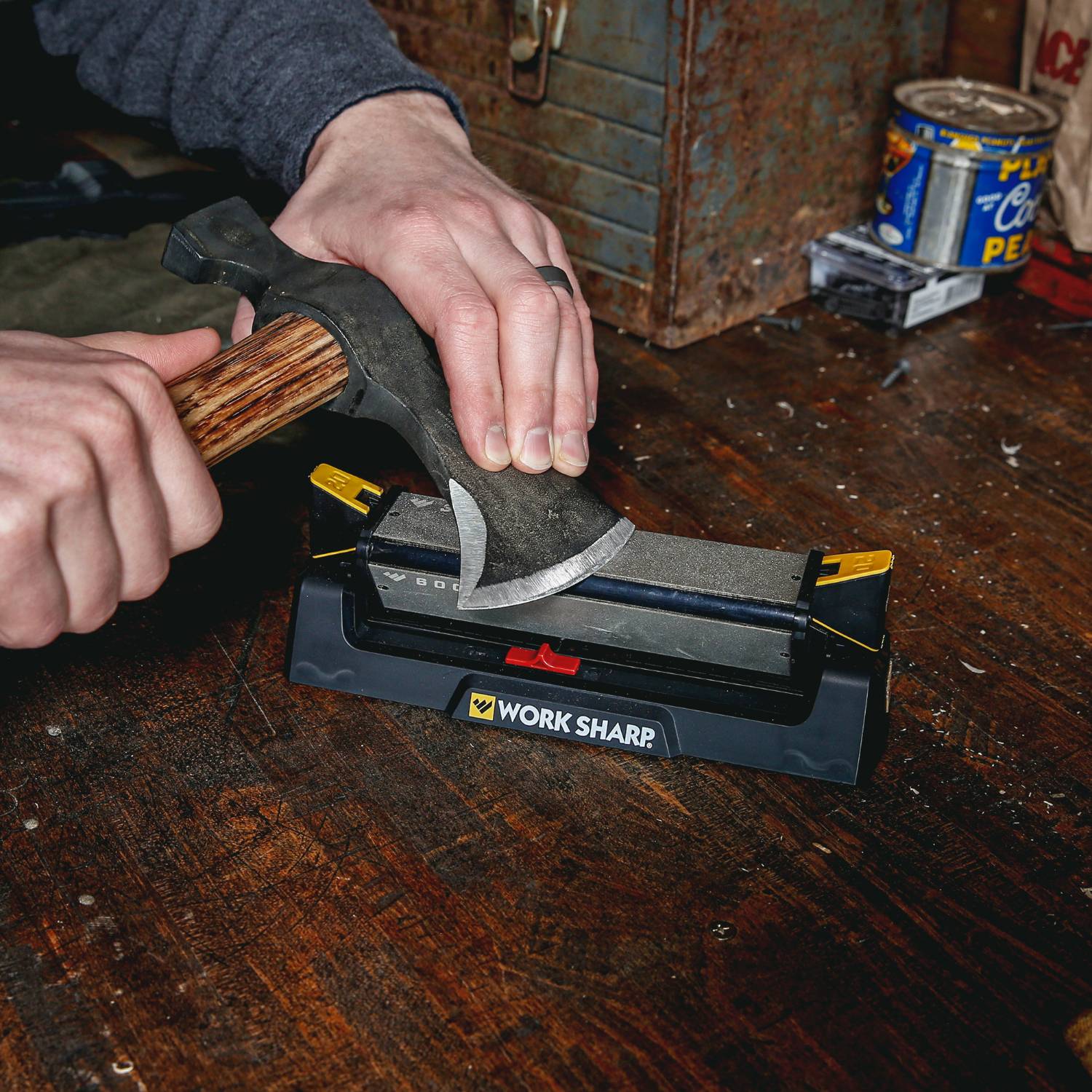 Person sharpening a woodworking hand tool blade on a Work Sharp Benchstone sharpening system on a wooden surface