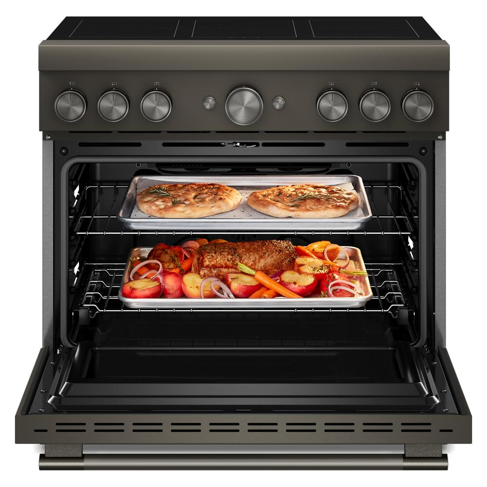 Open 36-inch induction range oven with trays of baked pizza and roasted vegetables with meat inside kitchen appliance