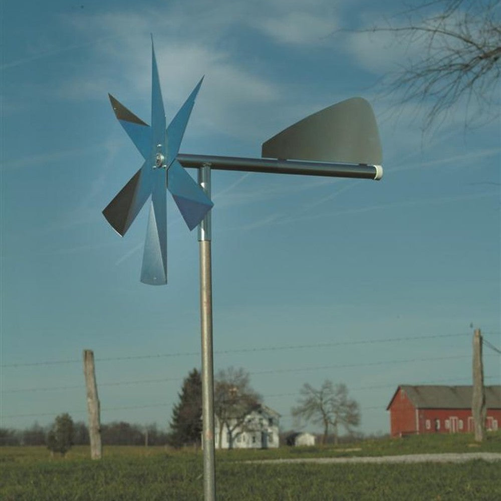 Metal windmill with multiple angled blades and a tail vane mounted on pole in grassy lawn for mole pest deterrence