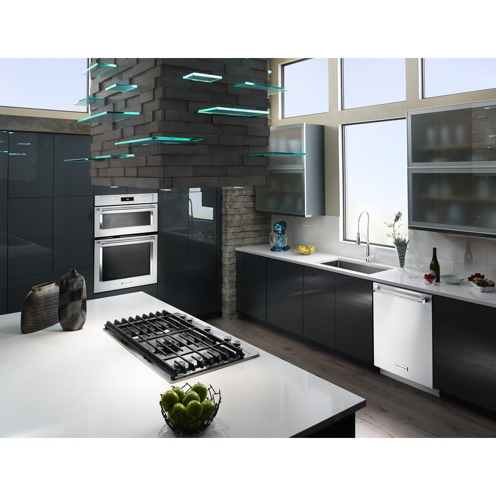 Modern kitchen with stainless steel 5-burner gas cooktop on white island and dark glossy cabinets in open layout