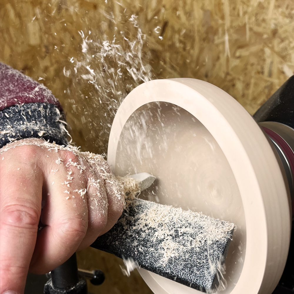 Hand shaping spinning wooden bowl on lathe with a 3/8 inch turning tool for woodworking and home improvement tasks