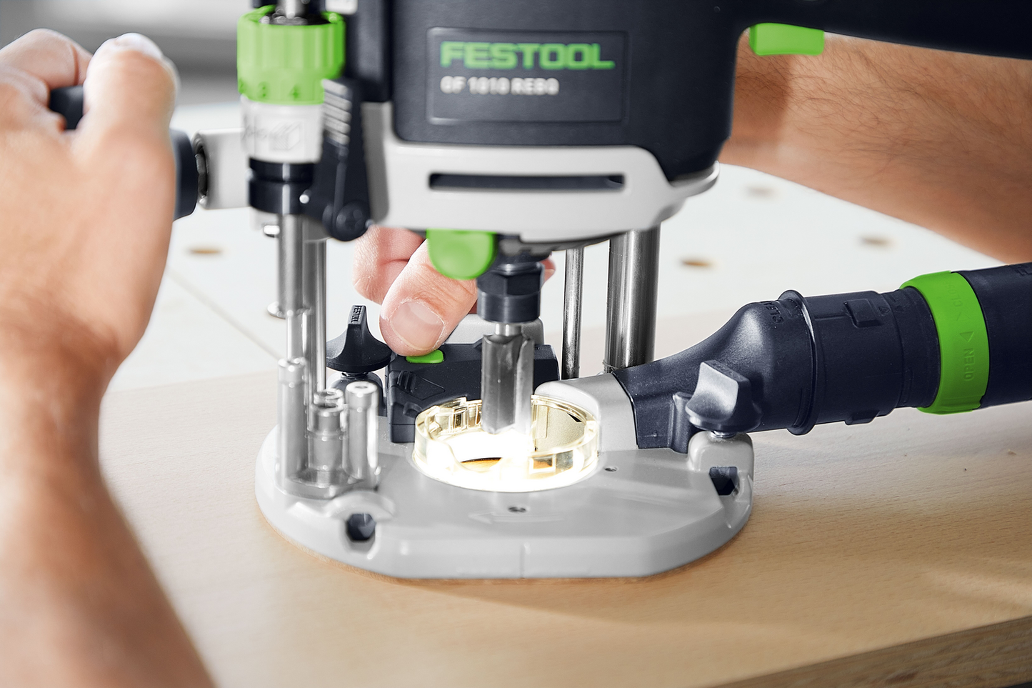Handheld precision router with ergonomic controls being adjusted for detailed woodworking on light wood panel