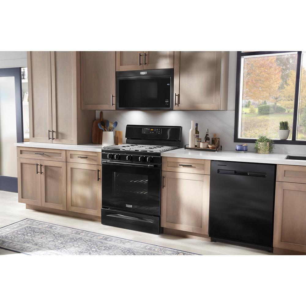 Black over-the-range flush built-in microwave above black stove in modern kitchen with light wood cabinetry