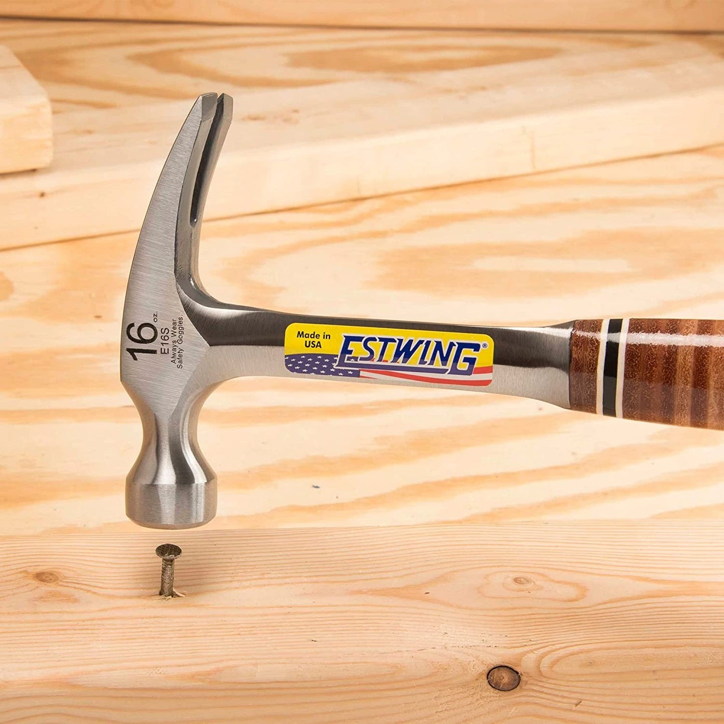 Claw hammer with leather-covered steel handle and forged head driving a nail, ideal for woodworking and hand tools under $100