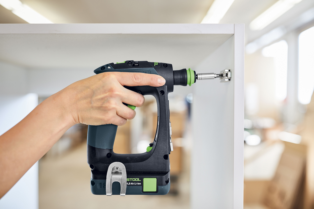 Hand using Festool 576887 CXS 18-Basic cordless drill to install hardware inside white cabinet for woodworking tasks