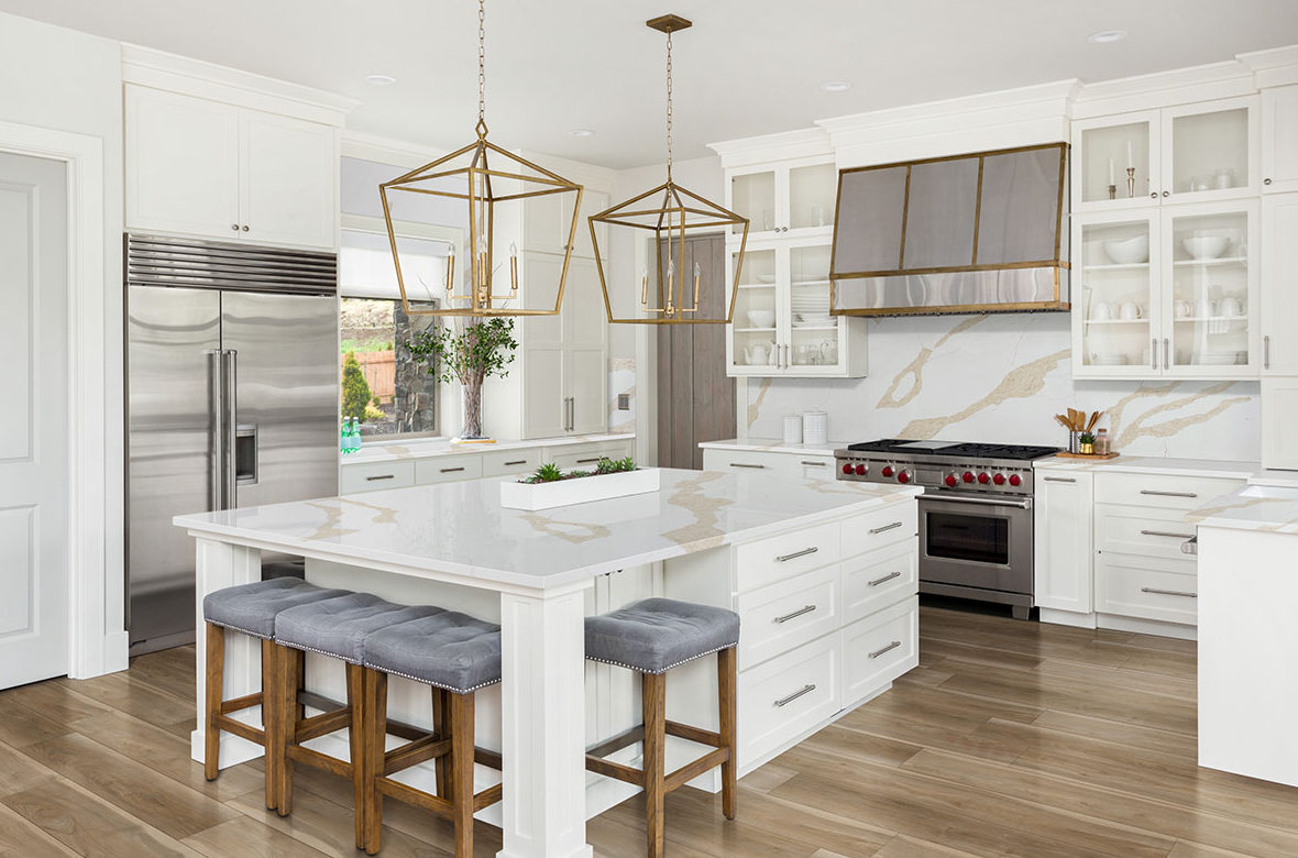 Modern kitchen with white cabinetry, gold pendant lights, large island seating, and wood-look luxury vinyl flooring