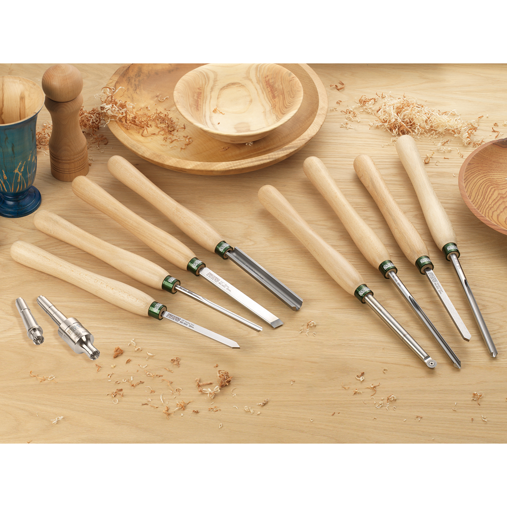 Set of woodturning tools with light wooden handles and various steel blades on a wooden surface with wood shavings