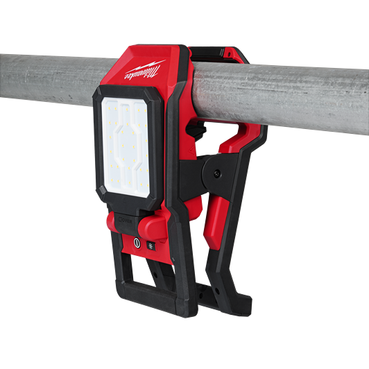 Red and black clamping LED flood light attached to a metal pipe for versatile Milwaukee utility lighting use