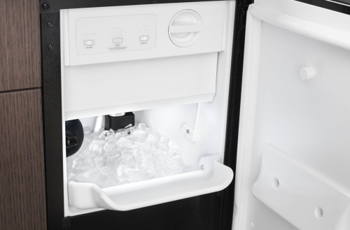 black undercounter icemaker with clear ice cubes and illuminated interior in kitchen appliances collection