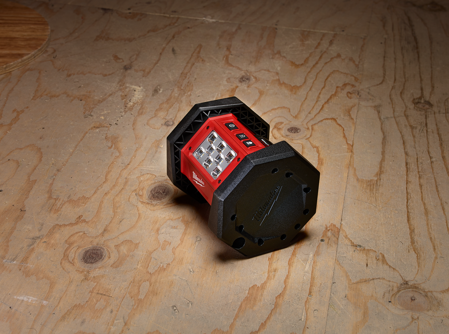 Compact red and black Milwaukee work light with multiple LEDs on wooden surface from Milwaukee Utility Lights collection
