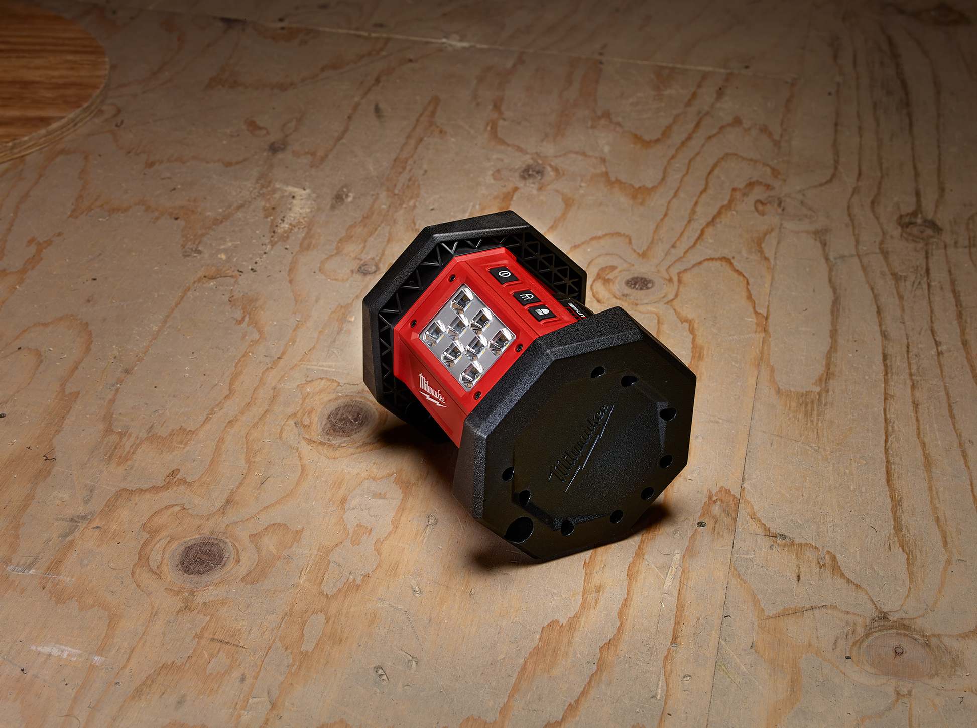 Compact red and black Milwaukee work light with multiple LEDs on wooden surface from Milwaukee Utility Lights collection