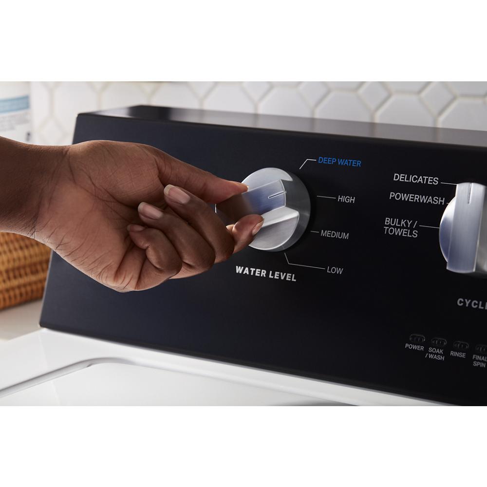 Hand adjusting water level dial on black control panel of commercial-grade top load washer from washers collection