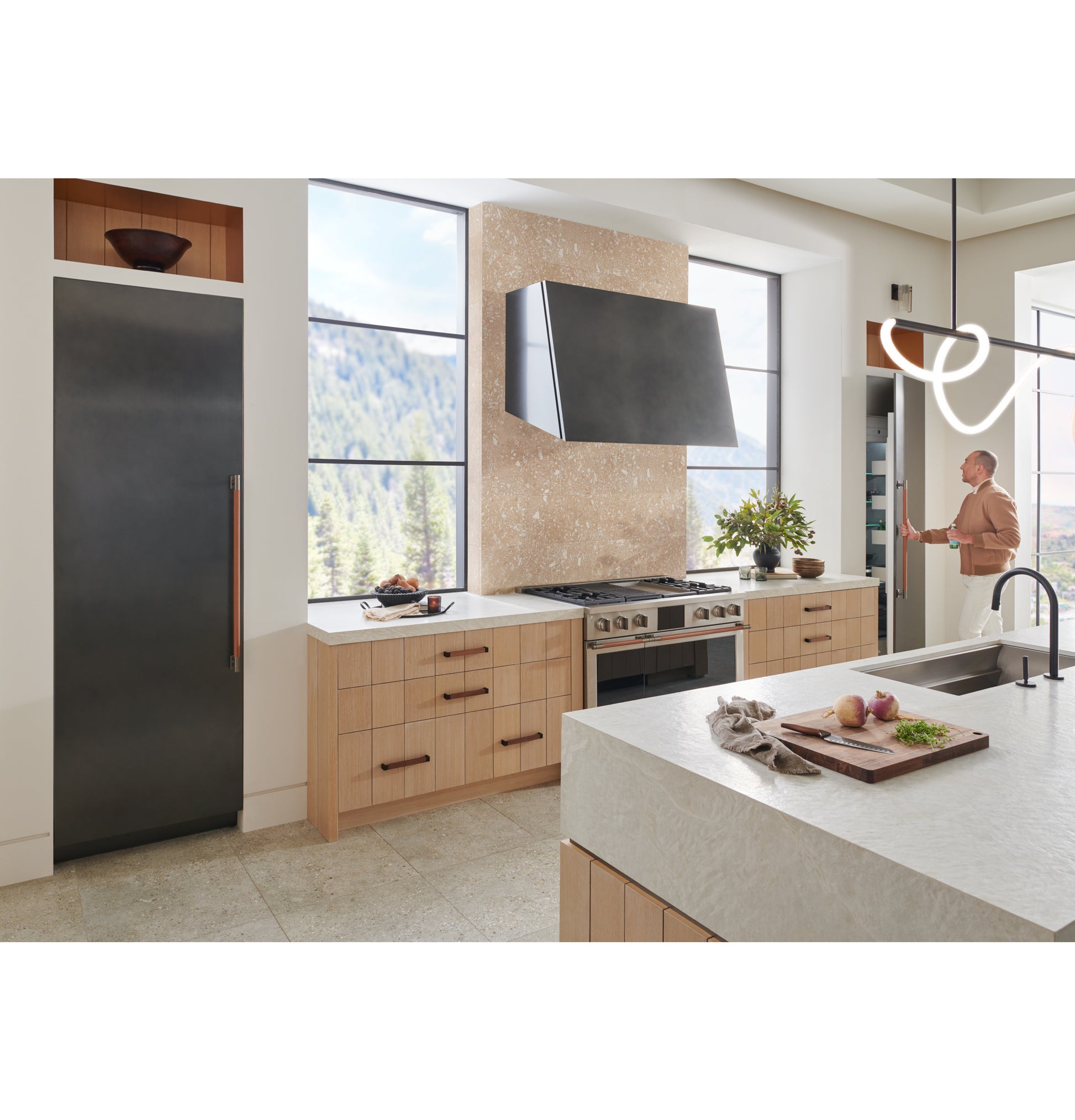 Contemporary kitchen featuring a titanium designer hood above stainless cooktop in over the range hoods and appliances collection