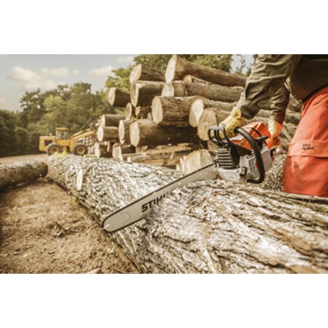 Person cutting large tree trunk outdoors using a stihl chainsaw with stacked logs and machinery in background