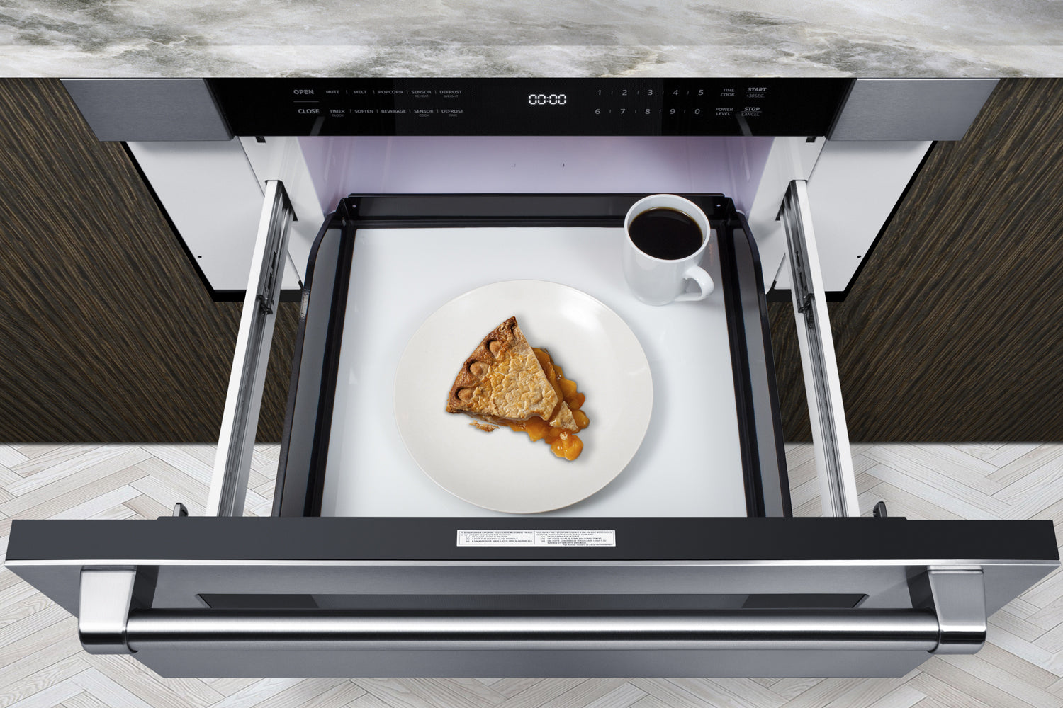 Modern stainless steel built-in microwave drawer open under countertop with pie slice and coffee cup inside