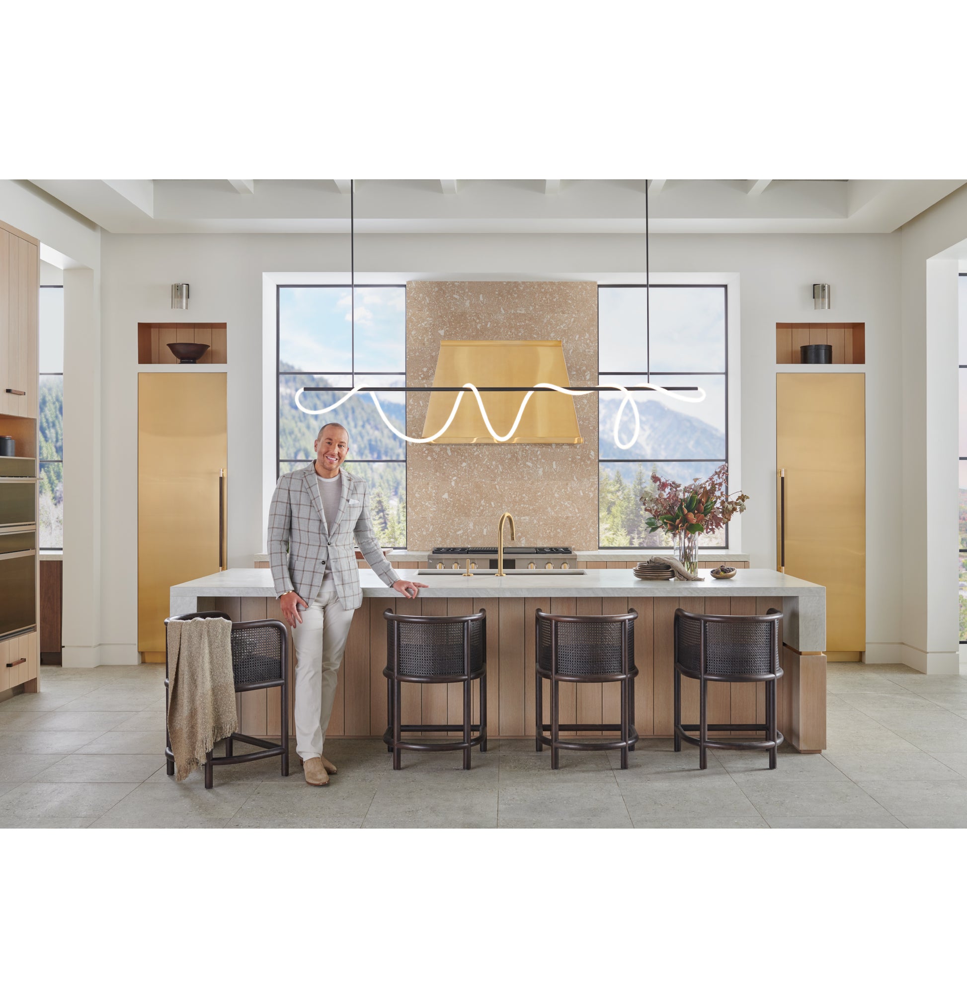 Spacious modern kitchen with brass designer hood, large windows, island seating, and minimalist decor in kitchenware collection