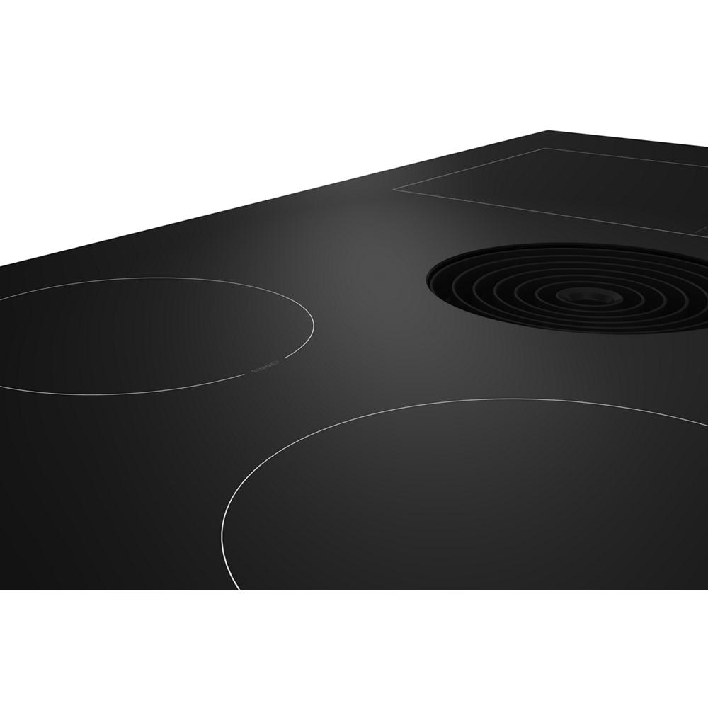 Close-up of a sleek black induction cooktop featuring a downdraft vent and smooth glass surface from KitchenAid appliances.
