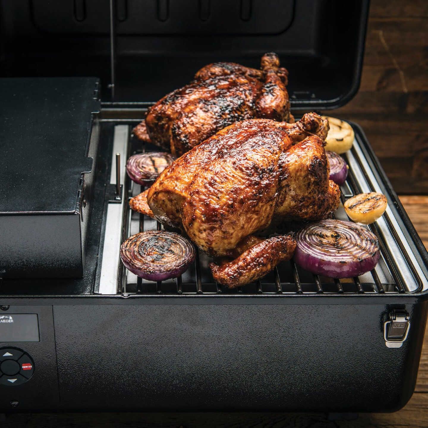 Two whole roasted chickens and grilled onions cooking on a black portable pellet grill for outdoor living.