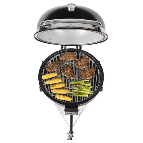 Black kamado-style charcoal grill with open lid grilling steaks, corn, and asparagus for outdoor cooking and grilling collections