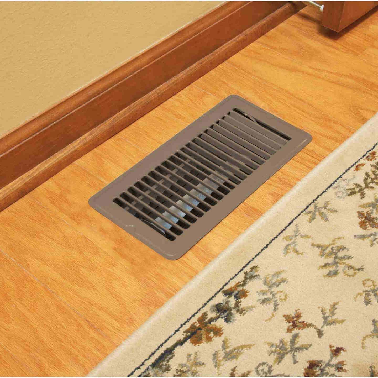 Brown steel floor register with adjustable vents installed in wood floor near patterned area rug for home improvement