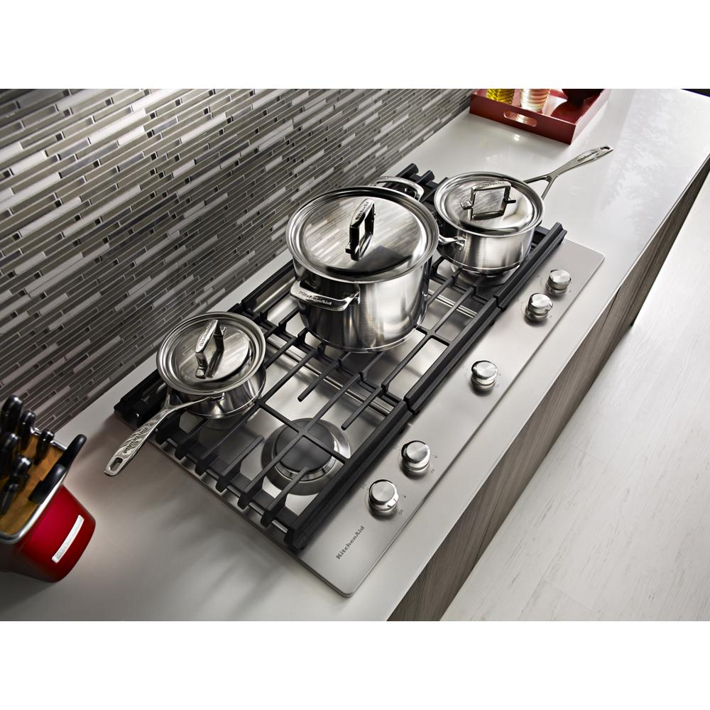 Top view of stainless steel 30-inch gas cooktop with five burners and cookware on black cast iron grates in modern kitchen