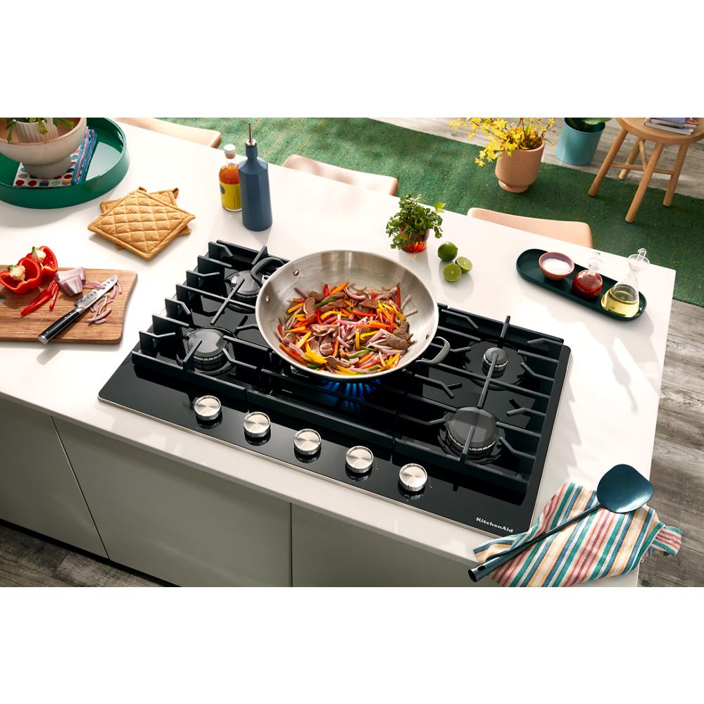 36-inch black glass cooktop with five burners and stainless steel knobs in a bright kitchen setting for home improvement.