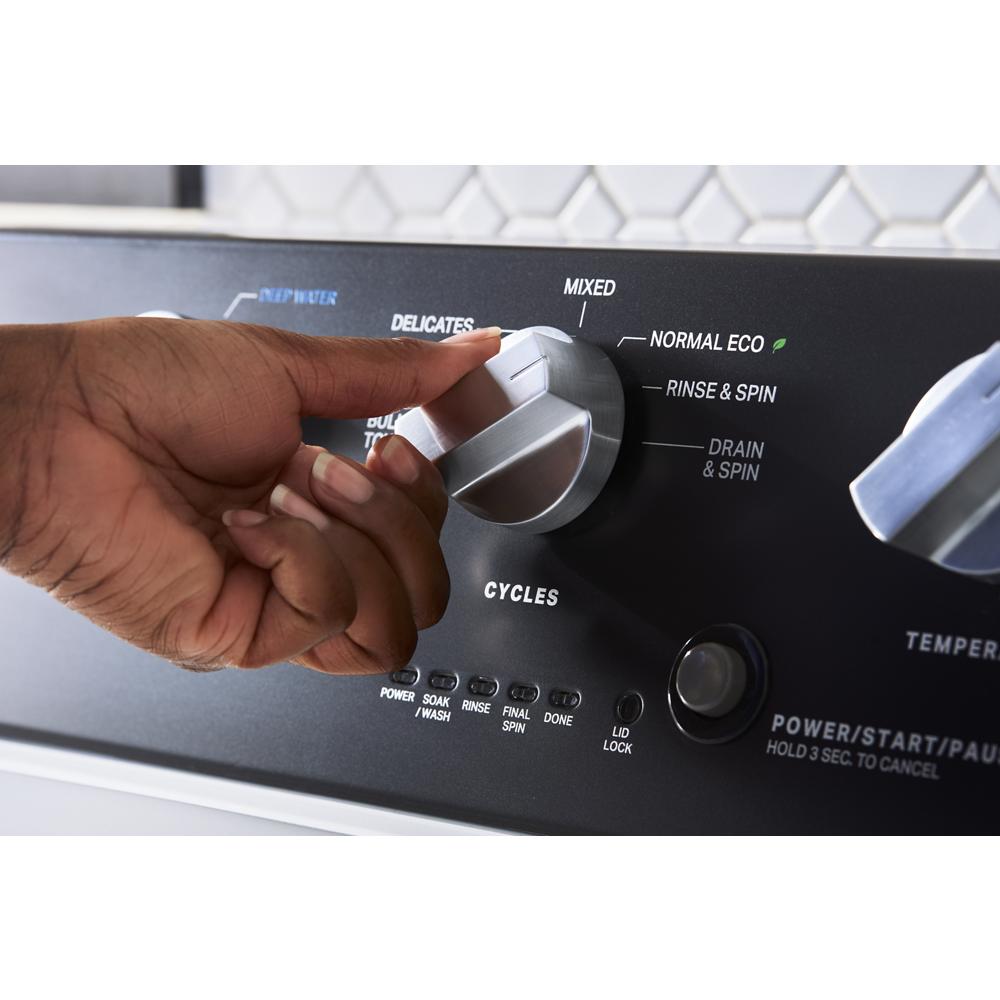 Hand adjusting cycle selector knob on control panel of a commercial-grade top load washer from washers collection