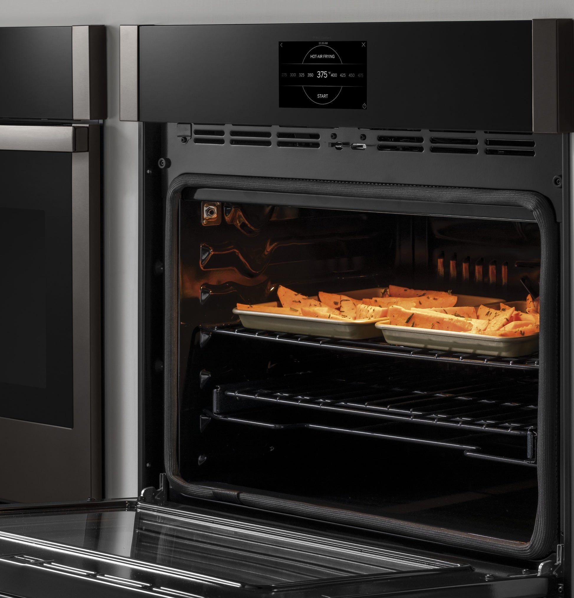Open built-in convection wall oven with tray of food cooking and digital control panel above door from kitchen appliances collection