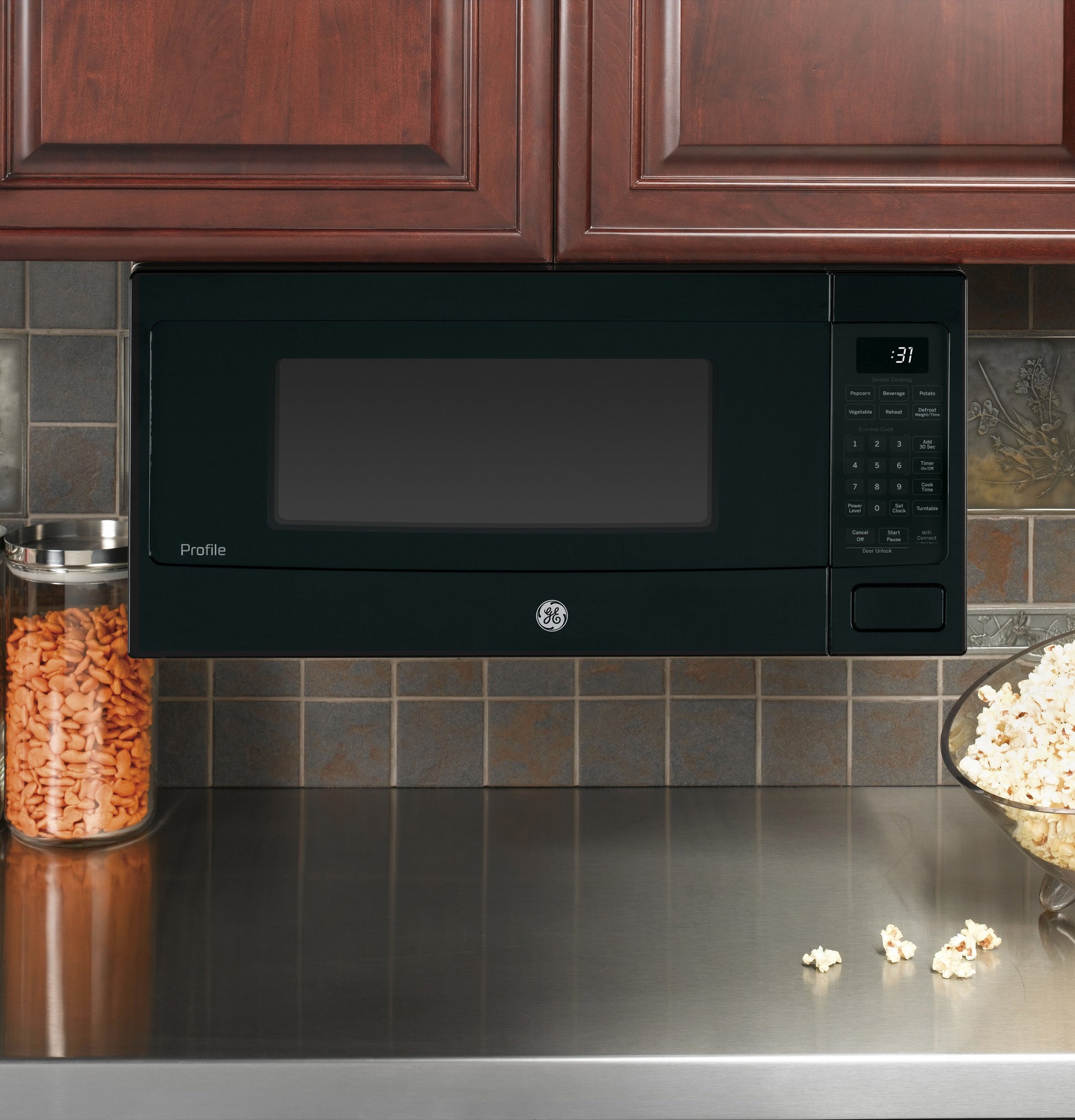 Black built-in microwave oven with digital control panel installed under kitchen cabinets above stainless steel countertop