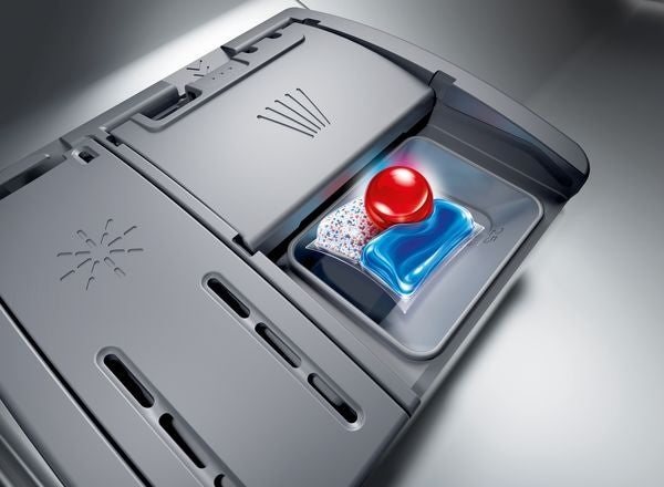 Close-up of dishwasher detergent compartment with blue and red detergent pod inside custom panel ready dishwasher drawer