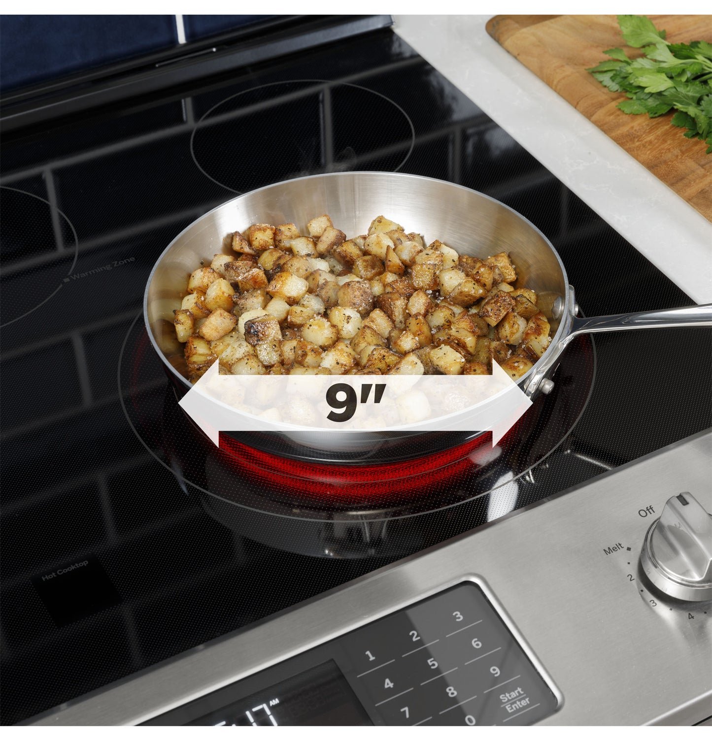 Close-up of stainless steel frying pan with cooked diced potatoes on 9-inch electric induction cooktop burner</125