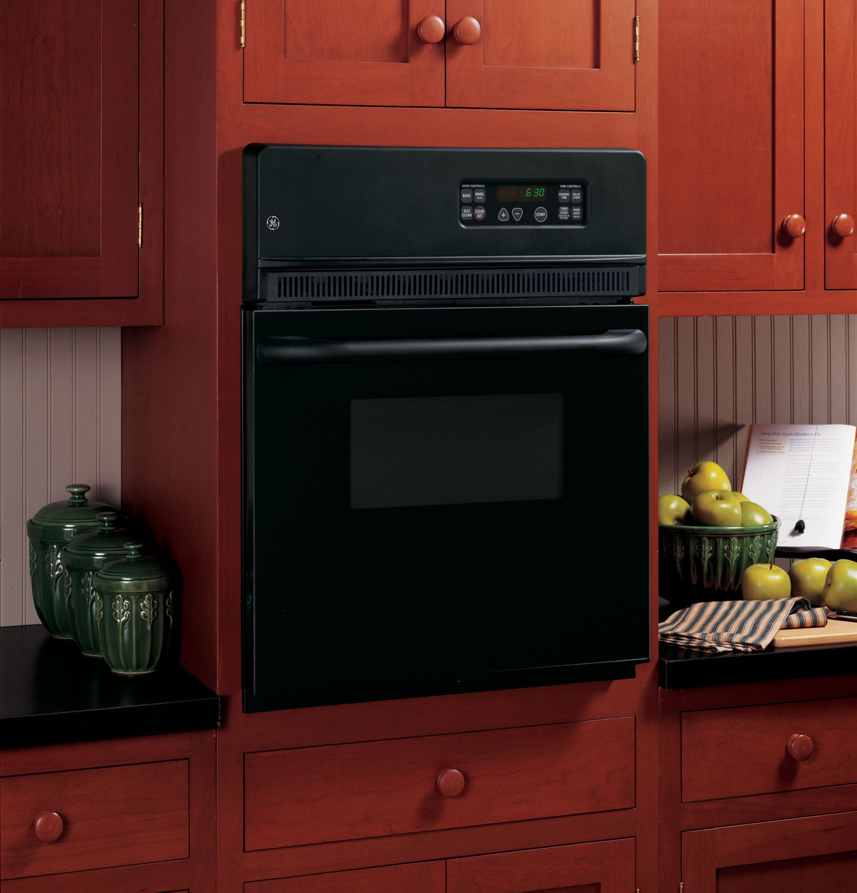 Built-in black electric single wall oven with digital display and control panel in traditional kitchen setting