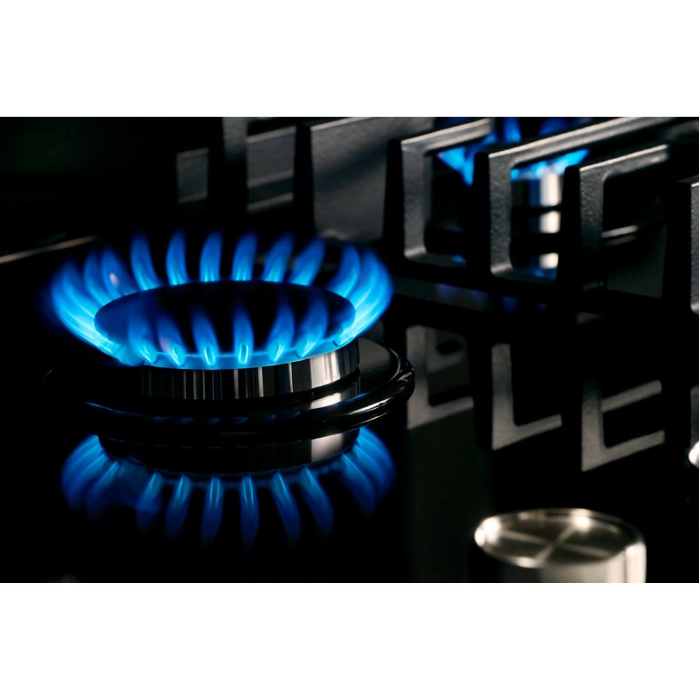 Close-up of blue flame burner on sleek black glass gas cooktop from KitchenAid appliances collection
